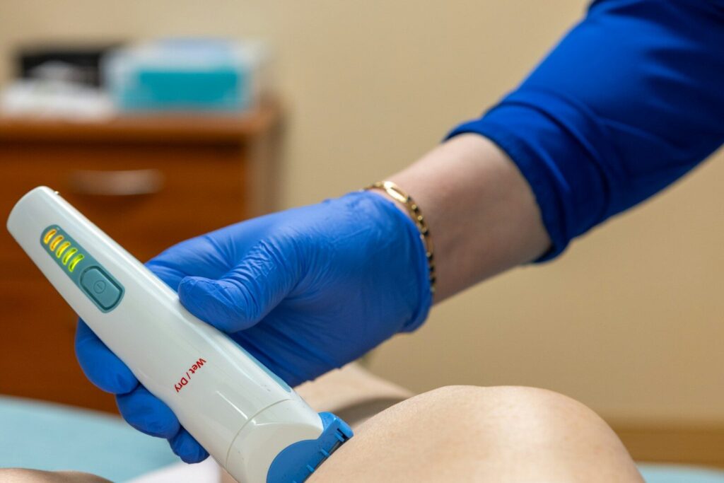 A medical professional using a laser device on a patient.